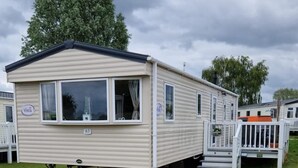 Une maison mobile de plain-pied, avec un toit plat, un porche à l’avant et le numéro « 63 » bien visible.