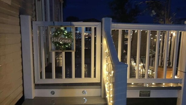 Une terrasse en bois avec une balustrade blanche et une pancarte indiquant «Bienvenue».