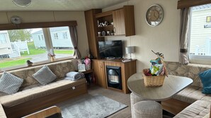 Un intérieur de camping-car chaleureux et confortable, avec un canapé, une table, un téléviseur et une cheminée.