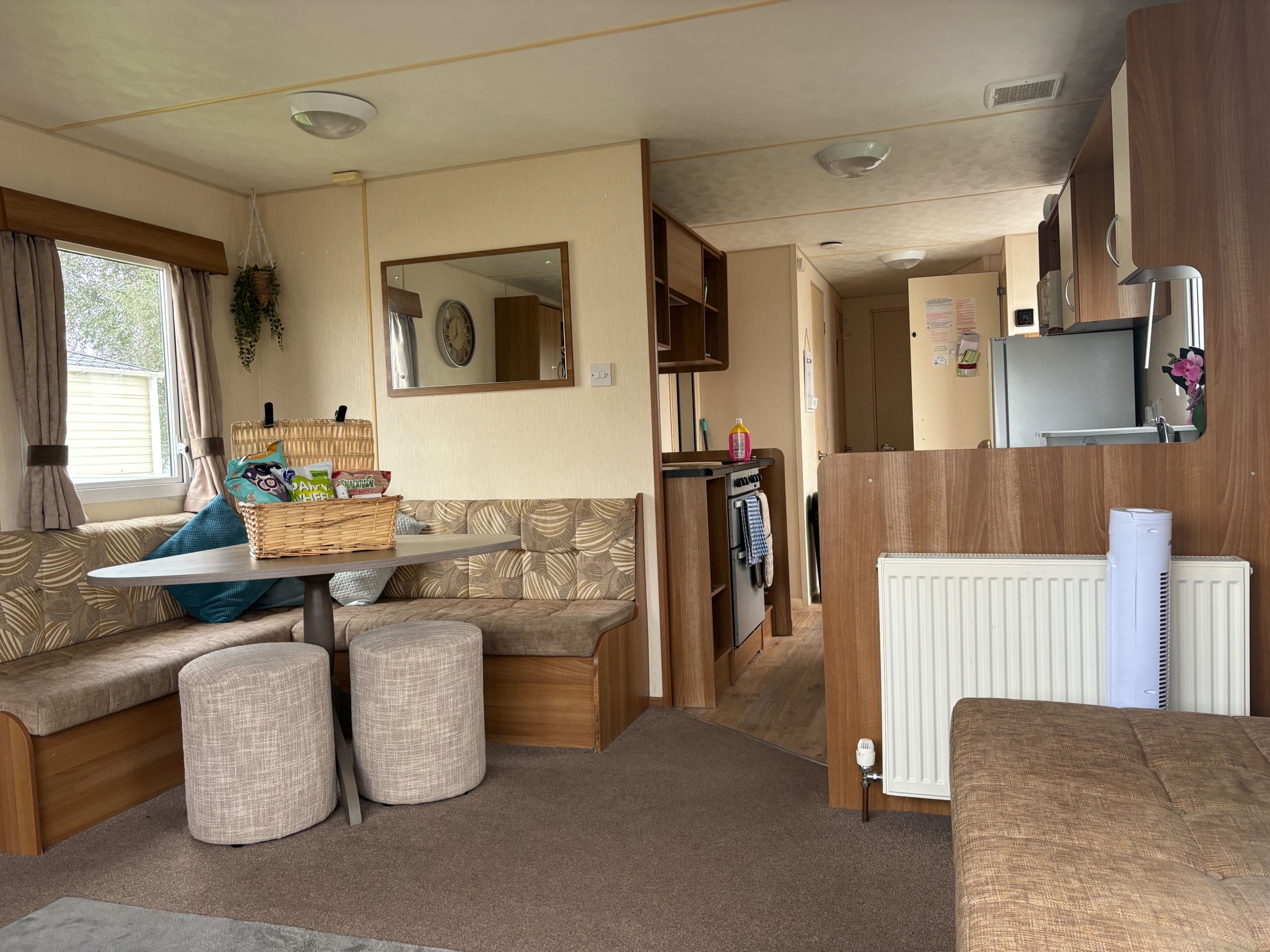 A cozy RV interior with a seating area, kitchenette, and a large mirror.