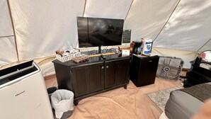 A tented accommodation area with a television, a coffee station, a fan, and a waste bin. - Stunning 1-bed Glamping Tent in Cleveland (Conroe)