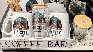 A coffee bar setup with a sign reading "Enjoy the farm fresh eggs & wine! Big City Little Farm", a bottle of Nestlé Coffee Mate French Vanilla, and branded mugs. - Stunning 1-bed Glamping Tent in Cleveland (Conroe)
