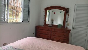 A bedroom with a bed, a dresser, a mirror, and a window. - Green slice (Mairinque)