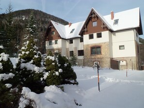 A multi-story building with a stone facade and wooden accents, surrounded by snow-covered trees.