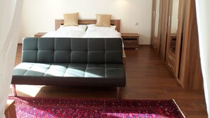 A bedroom with a large bed, two bedside tables, a wardrobe, and a red patterned rug. - Villa Wellspacher - Private Luxury Family Apartment 2 in Semmering - Ski Holiday (Semmering-Kurort)
