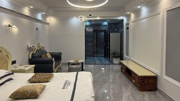 Une chambre d’hôtel moderne comprenant un lit, un coin salon et un couloir menant à une porte.