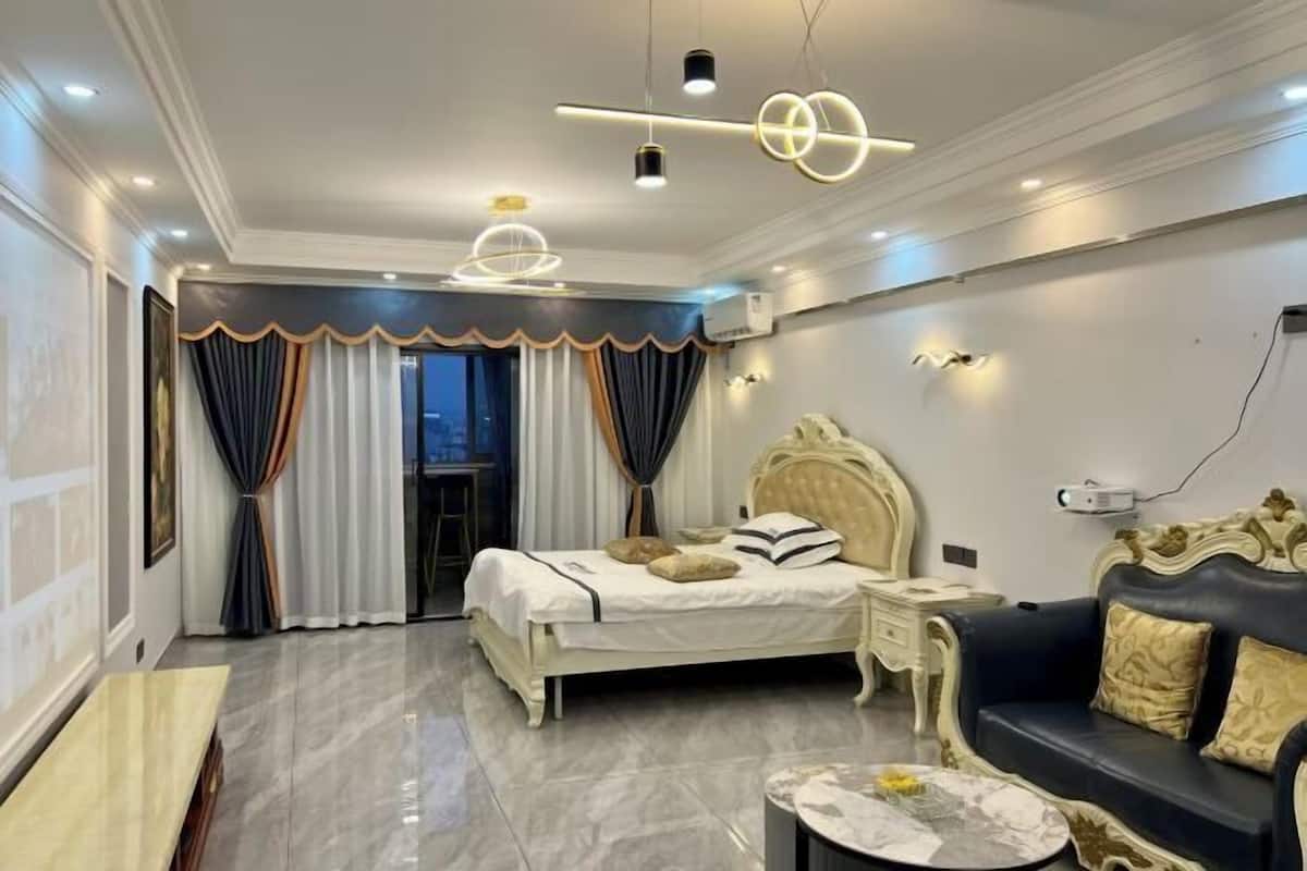 A bedroom with a bed, bedside tables, a sofa, and a coffee table.