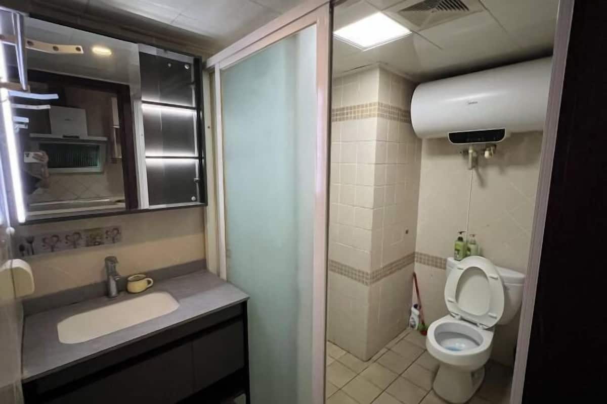 A bathroom with a sink, mirror, toilet, and shower.