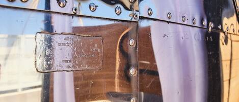 Ein Detailaufnahme einer glänzenden Metalloberfläche mit Nieten und einem Aufkleber mit der Aufschrift 'AIRSTREAM CERREITOS 9903 80-4 2614-85021'.