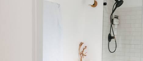 A modern bathroom with a freestanding bathtub, a glass shower enclosure, and a white tiled wall.