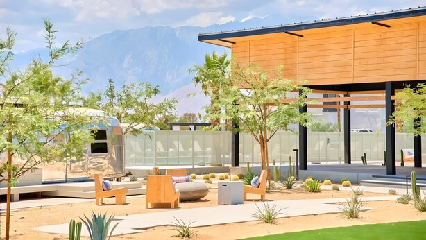 A modern outdoor patio with seating, a pool, and a mountain backdrop. - Acres Landing (Desert Hot Springs)
