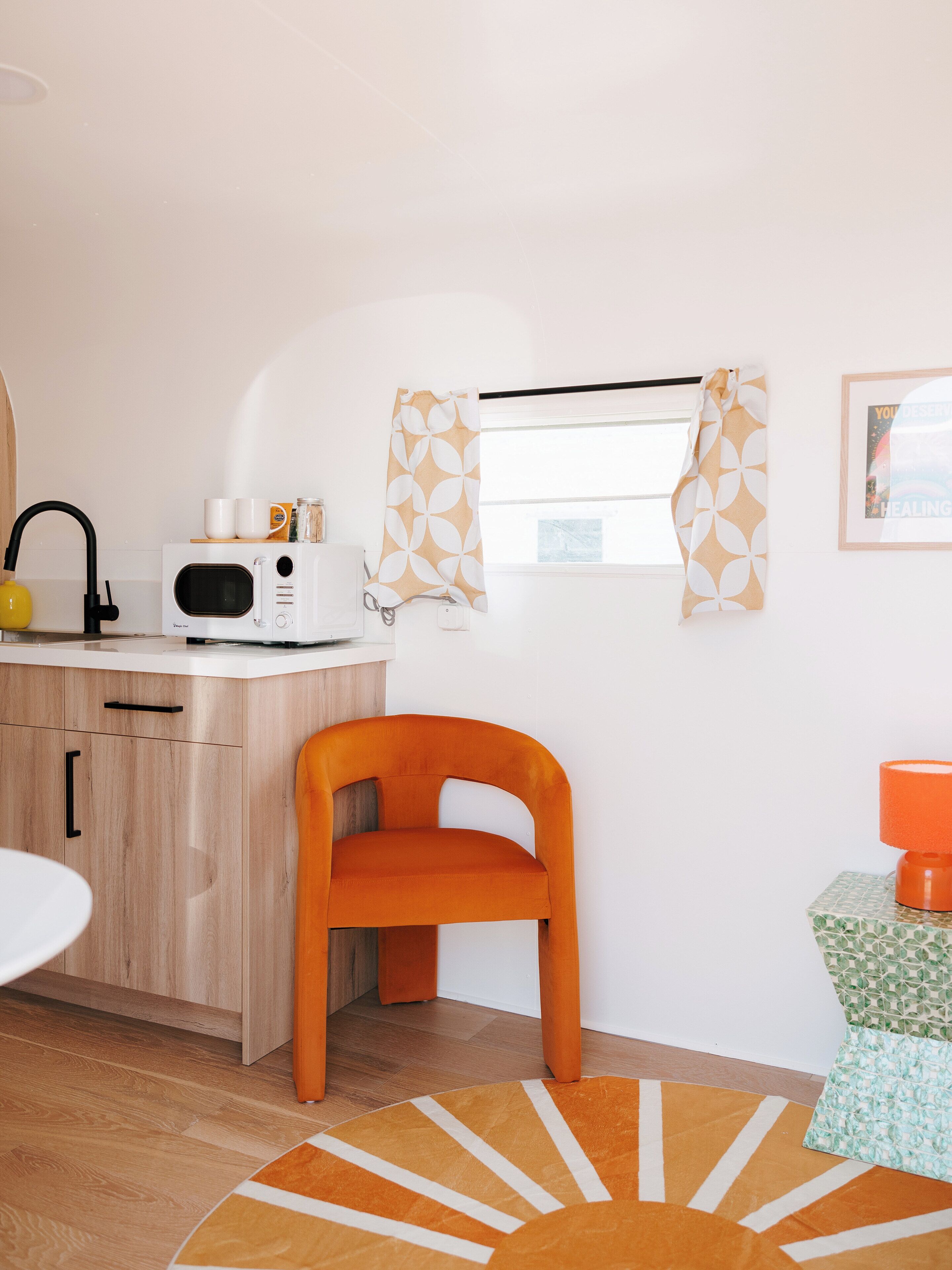 A compact kitchen with a microwave, a wooden cabinet, and a small table.