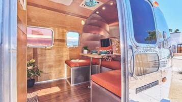 A compact RV interior with a kitchenette, seating area, and a small window.
