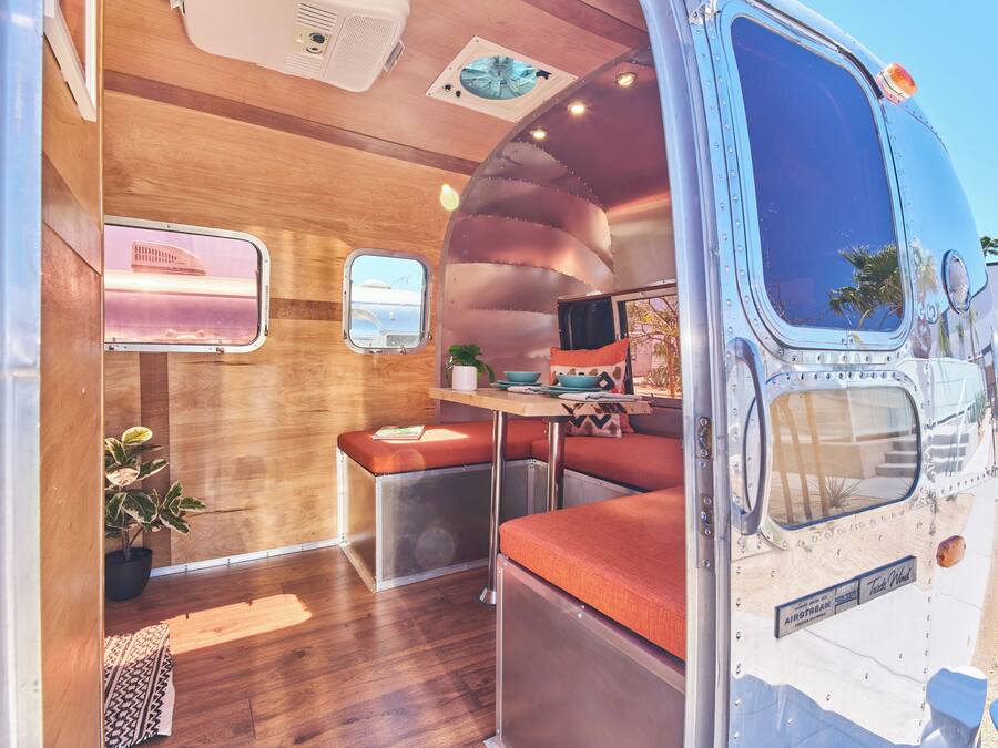 A compact RV interior with a kitchenette, seating area, and a small window.