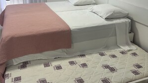 A single bed with a pink blanket, white pillows, and a patterned mattress. - Flat Iate Plaza Vista Incrível! (Mucuripe Fortaleza)