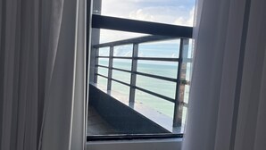 A room with a view of the sea through a window with a metal railing. - Flat Iate Plaza Vista Incrível! (Mucuripe Fortaleza)