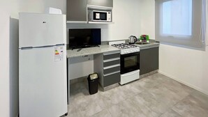 Une cuisine compacte équipée d’un réfrigérateur, d’un four à micro-ondes, d’une cuisinière et d’un four.