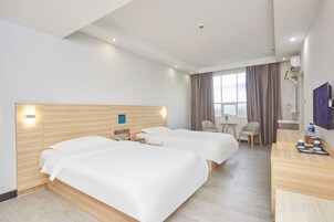 Una habitación de hotel con dos camas, un escritorio, una silla y un ventanal con cortinas.
