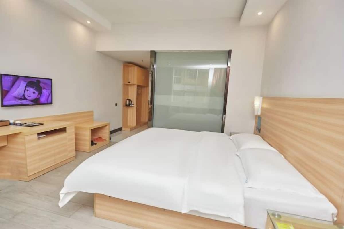 Ein modernes Hotelzimmer mit einem großen Bett, Holzmöbeln, einem Fernseher und einem Schiebetürenschrank.