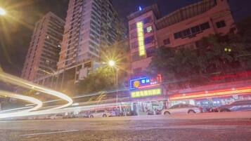 A nighttime cityscape with tall buildings, streetlights, and illuminated signs.
