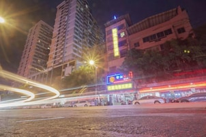 Un paisaje urbano nocturno con edificios altos, farolas y letreros iluminados.