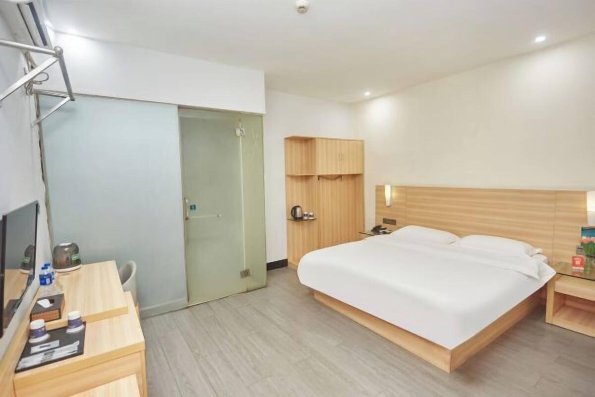 Ein Hotelzimmer mit einem Bett, einem Schreibtisch, einem Fernseher, einem Kleiderschrank und einer Tür.