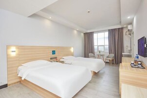 Habitación de hotel con dos camas, un escritorio, una silla, una mesita y una ventana con cortinas.