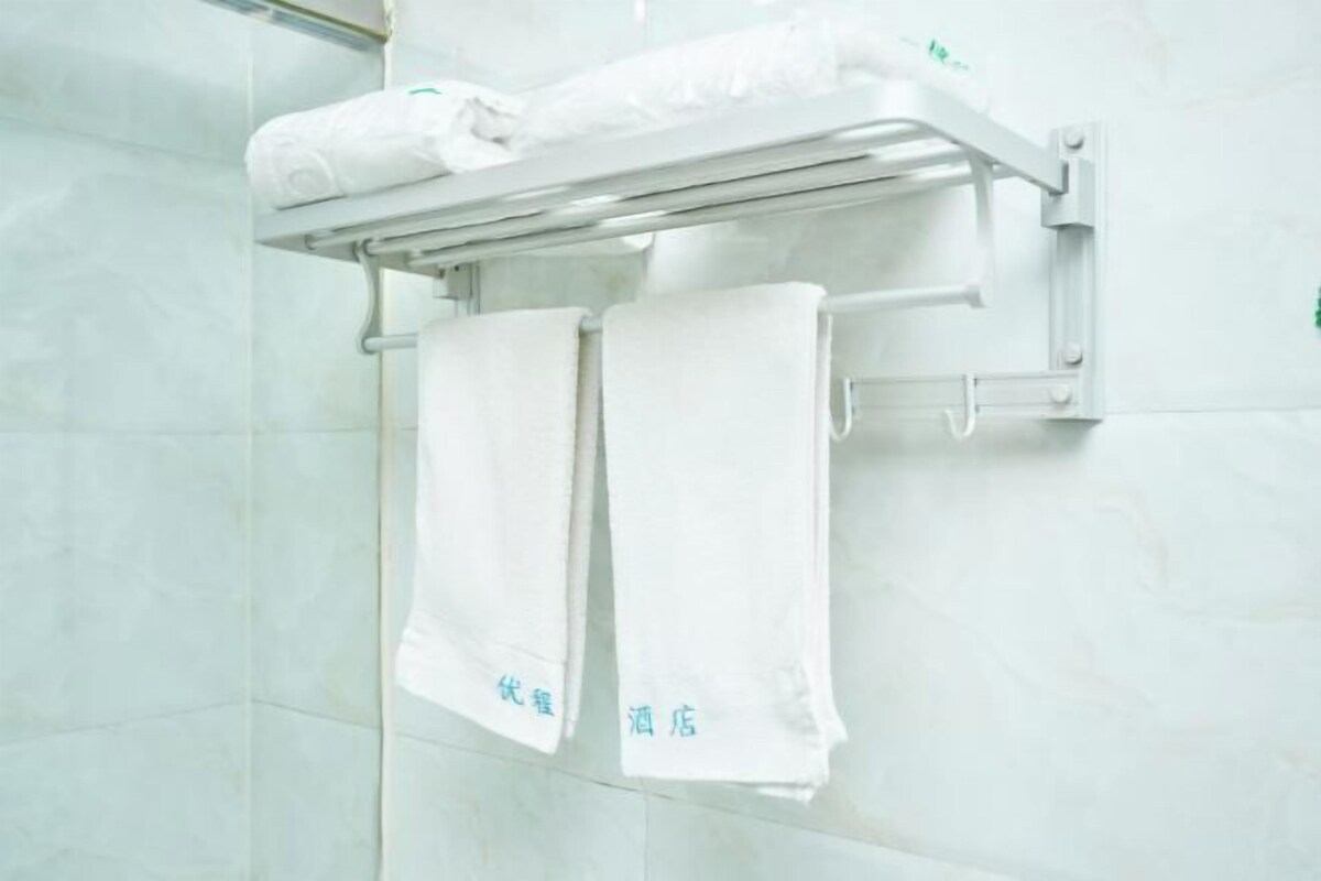 Un baño con un perchero que sostiene dos toallas blancas y una toalla doblada sobre una repisa.