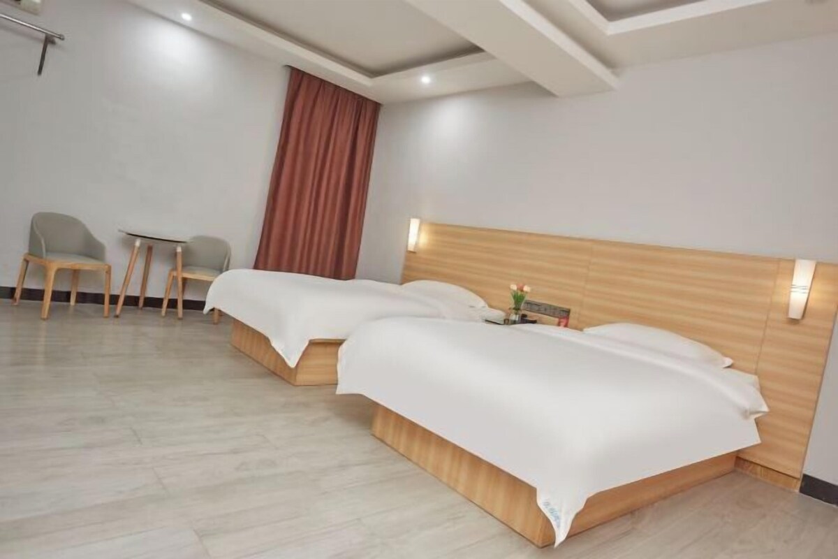Habitación de hotel con dos camas, una mesita pequeña y dos sillas.