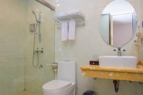 A bathroom with a glass-enclosed shower, a toilet, a sink with a mirror, and a towel rack. - Balihotel (Wuxuan)