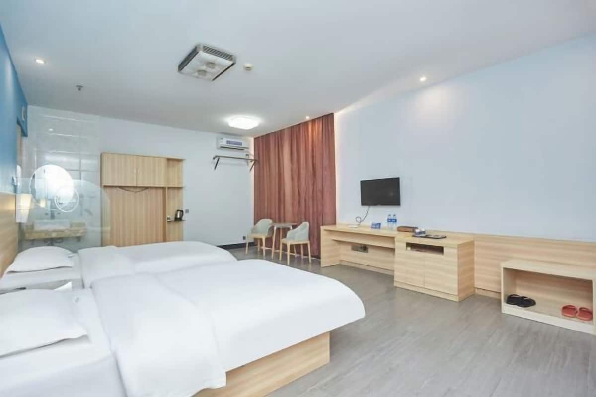 Ein Hotelzimmer mit Bett, Schreibtisch, Sessel, Fernseher und Schuhablage.
