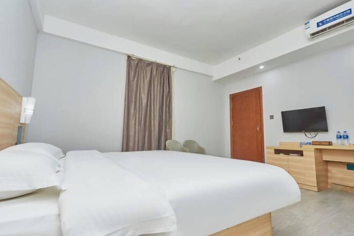 Una habitación de hotel con una cama, un escritorio, un televisor y un aire acondicionado.