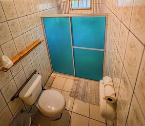 Bathroom features a toilet, shower enclosure, and storage shelf.