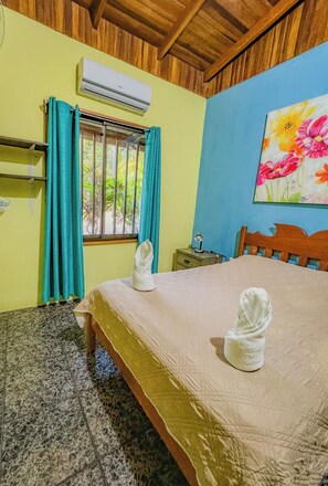 Relax in this inviting room with a comfortable bed, a nightstand, and a window with curtains.