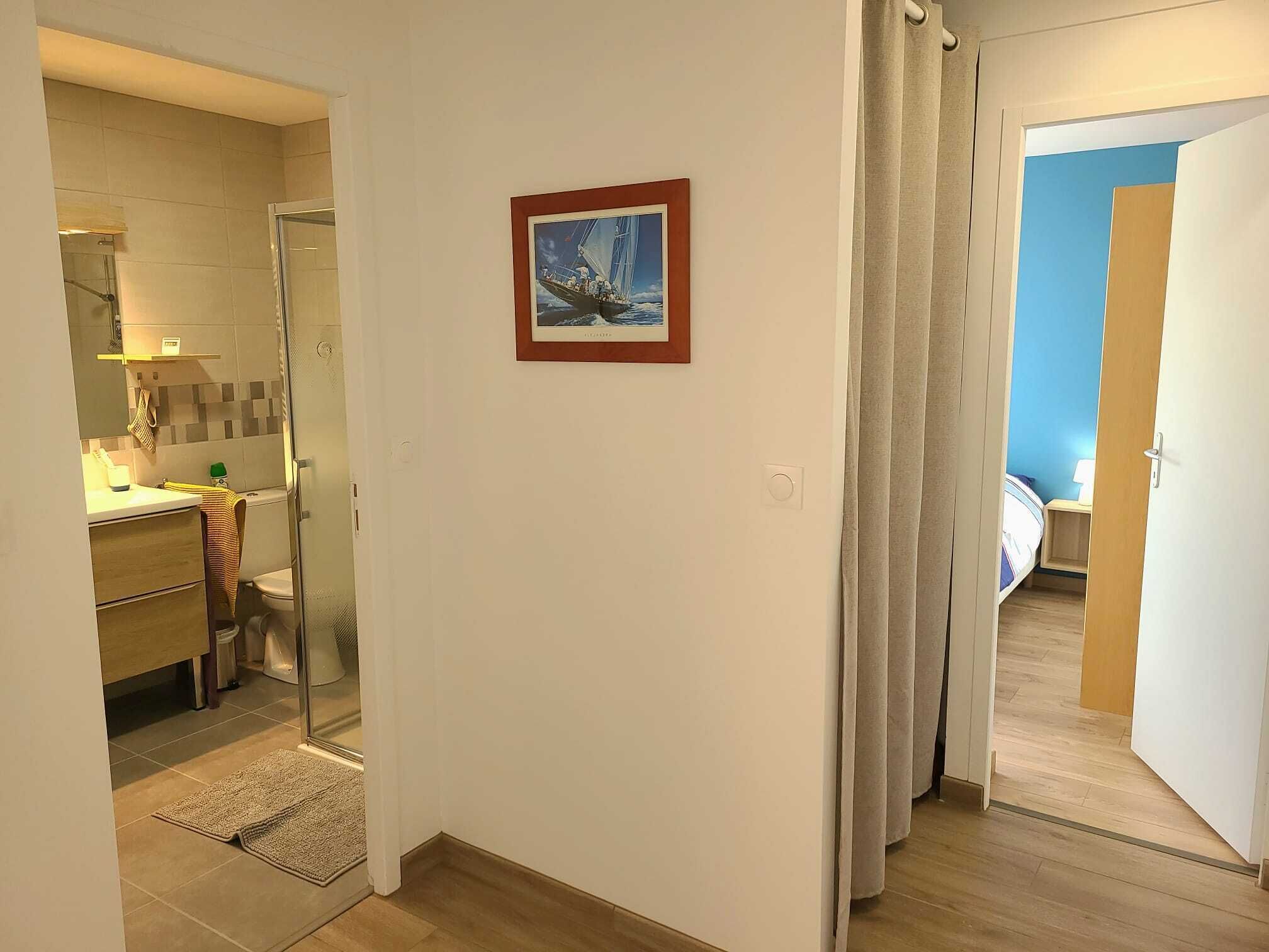A hotel room with a bathroom, a small kitchen area, and a bedroom.