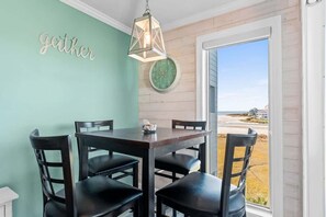 A dining area with a table and chairs, a wall clock, and a 'gether' sign. - ONE More Sandy Day - 2BR/2BA Beach Condo, Sleeps 6 (Myrtle Beach)
