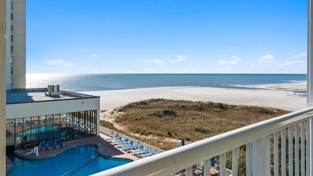 A pool area with lounge chairs and a view of the beach. - ONE More Sandy Day - 2BR/2BA Beach Condo, Sleeps 6 (Myrtle Beach)