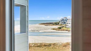 A view from inside a building looking out to a beach with a house in the background. - ONE More Sandy Day - 2BR/2BA Beach Condo, Sleeps 6 (Myrtle Beach)