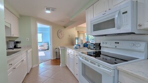 A kitchen with white cabinets, a microwave, a stove, and a coffee maker. - Exceptional location!  Across the street from the beach! Walk to Everything!  (Hilton Head Island)
