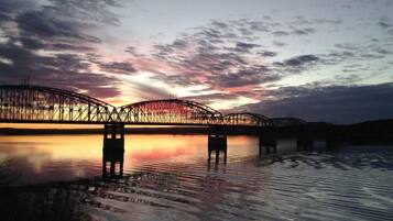 Eine Brücke über Wasser, im Hintergrund ein Sonnenuntergang.