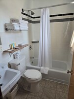 Bañera con ducha, toallas, jabón, shampoo