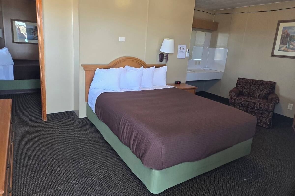 Ein Hotelzimmer mit einem großen Bett, einem Sessel, einem Schreibtisch und einem Spiegel.