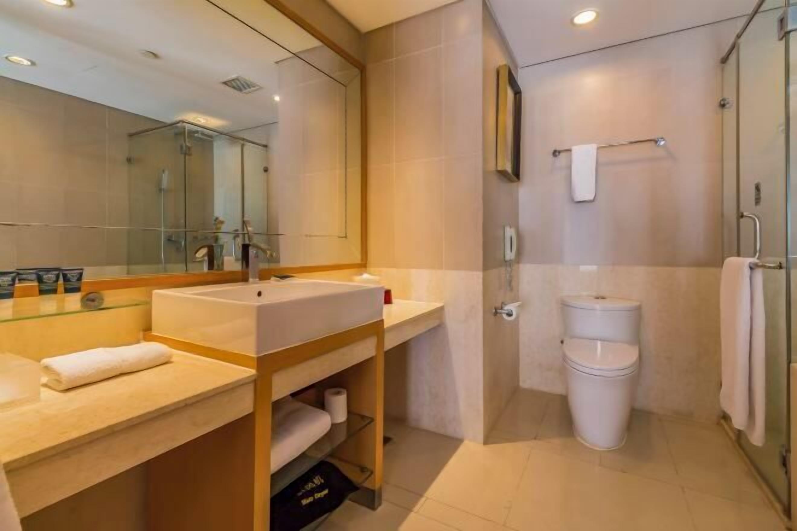Een moderne badkamer met een grote spiegel, een wastafel, toilet en een douchecabine met glazen wanden.
