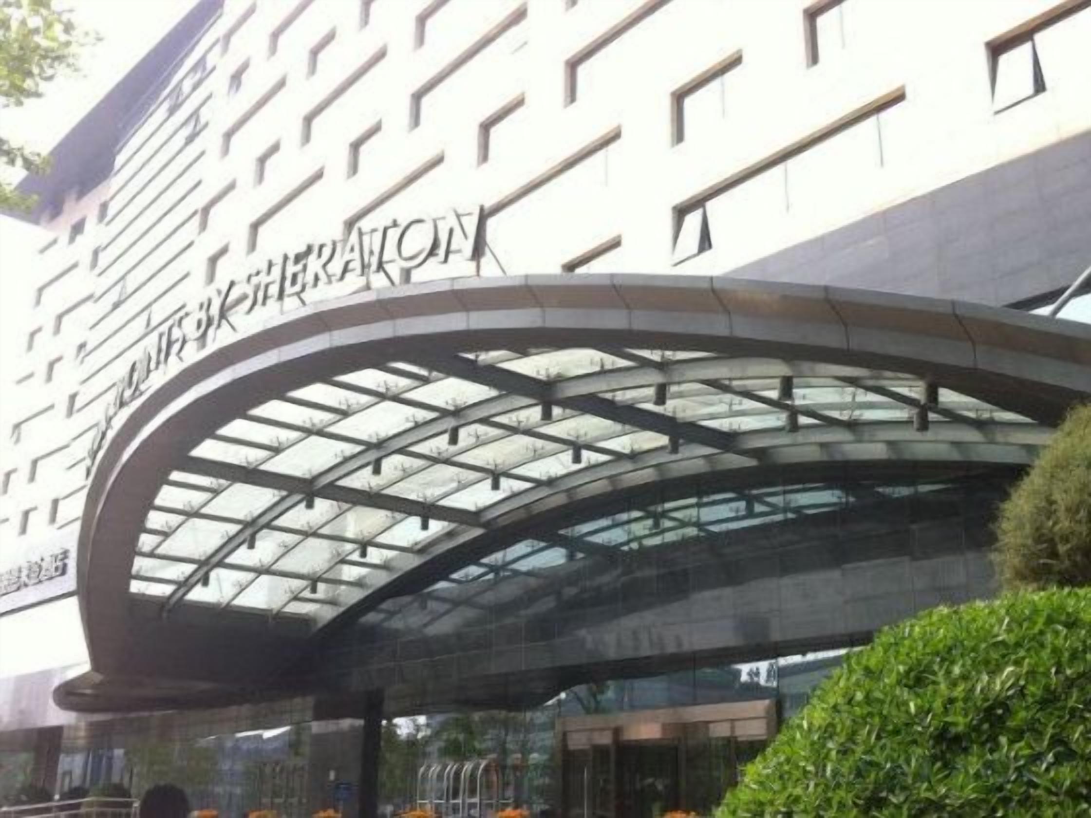 A hotel entrance with a curved glass canopy and a sign above it.