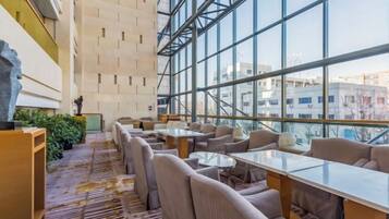 A spacious indoor area with multiple seating arrangements, large windows, and a view of the cityscape.