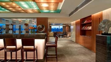 A hotel lobby with a reception desk, seating area, and a bookshelf.