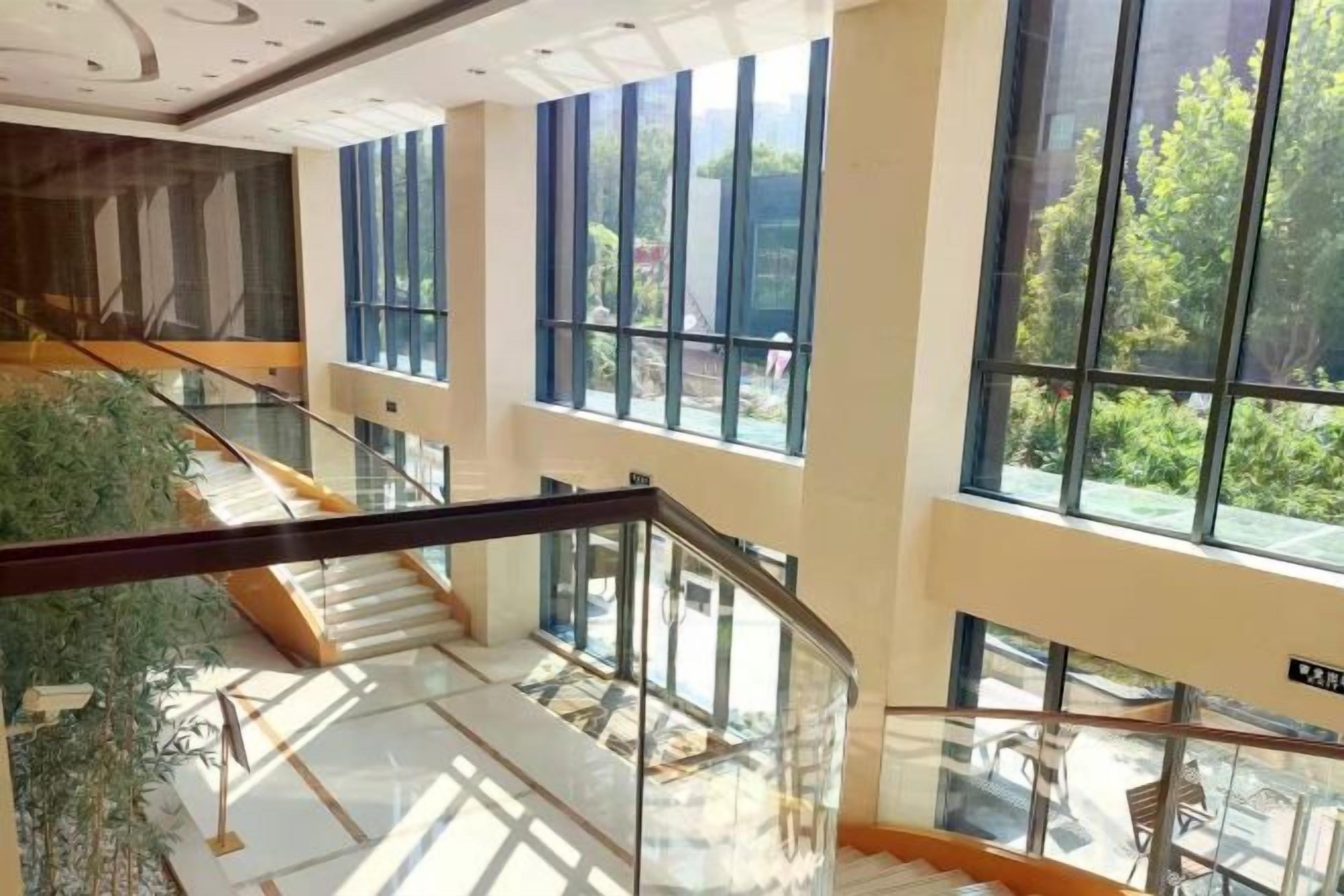 A multi-level interior with glass railings, a staircase, and large windows.