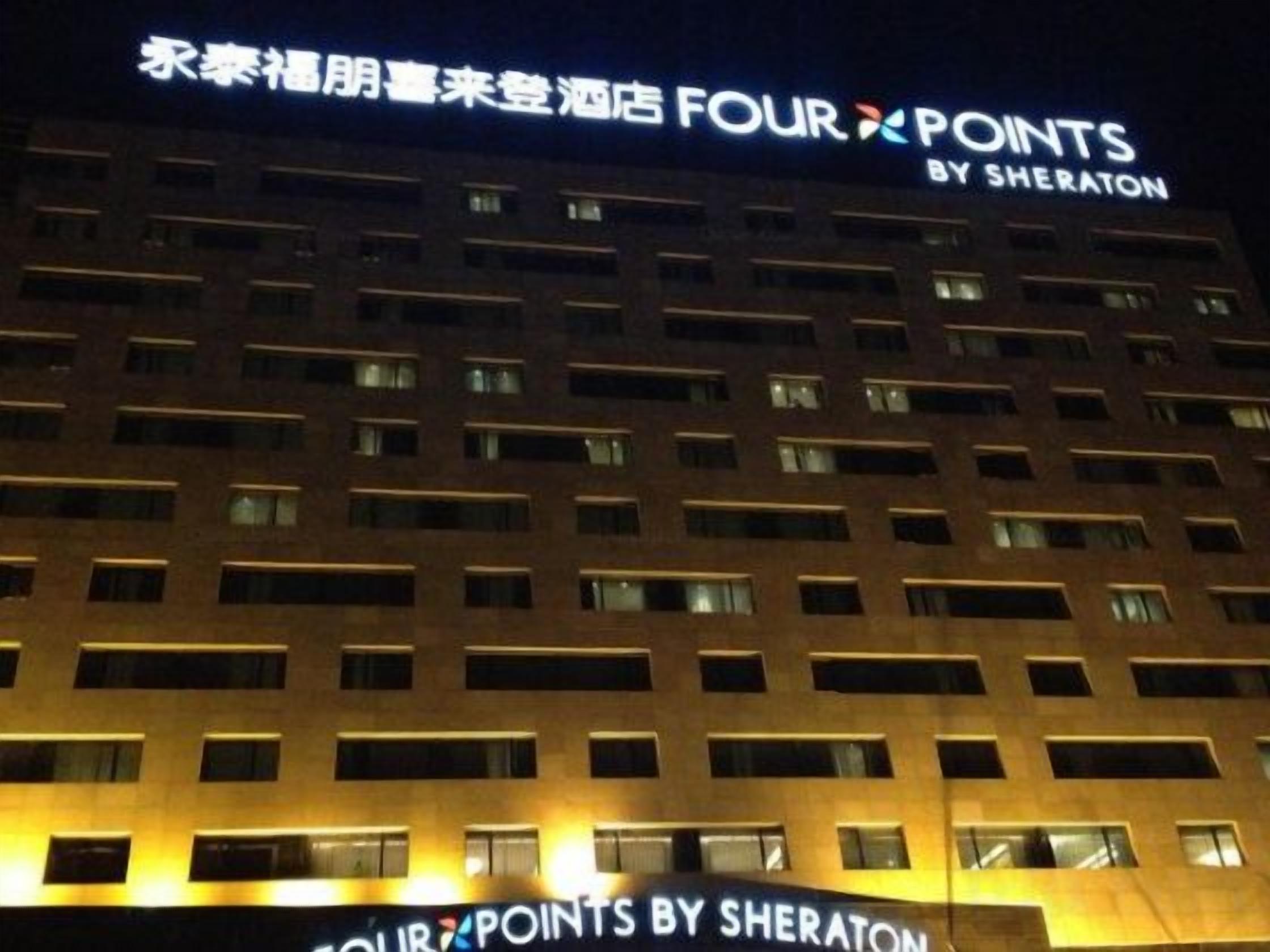 A hotel building with illuminated signage reading 'FOUR POINTS BY SHERATON'.