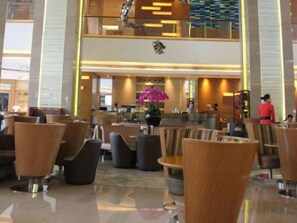 A hotel lobby with multiple seating areas, a reception desk, and a decorative ceiling feature.
