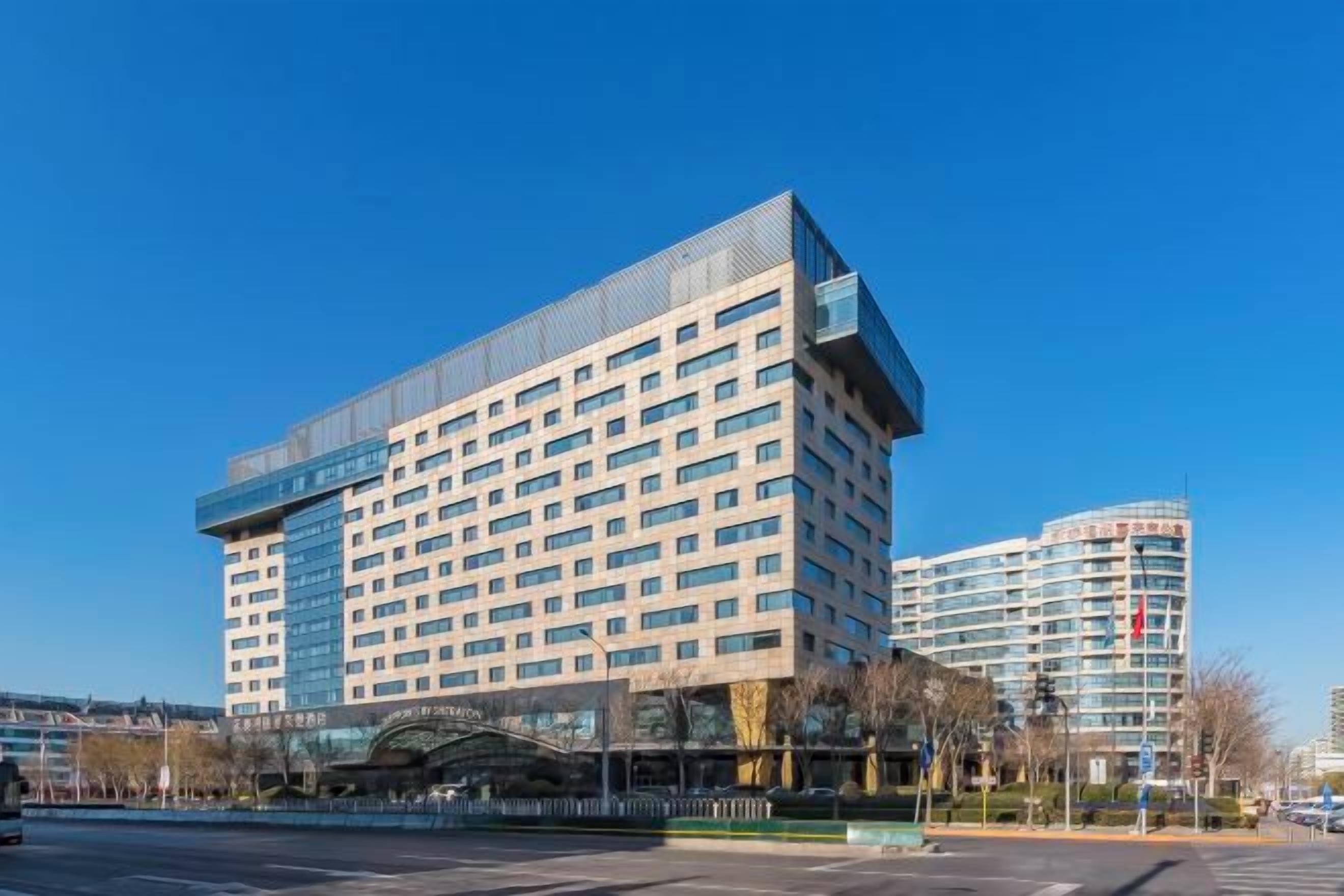A modern hotel with a flat facade, multiple floors, and a prominent entrance.
